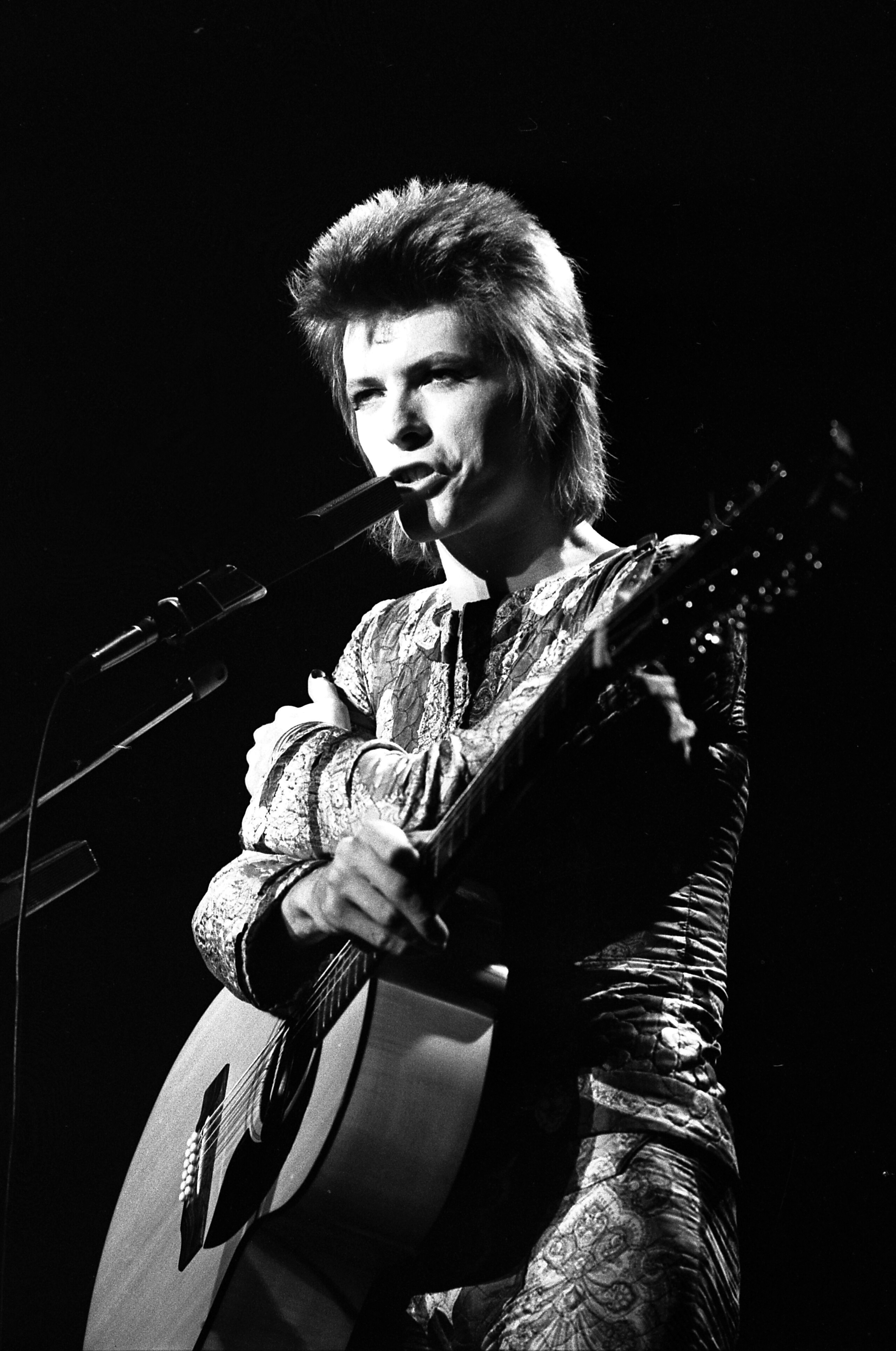 David Bowie nei panni di Ziggy Stardust canta al microfono e suona la chitarra al Santa Monica Civic Auditorium nel 1972