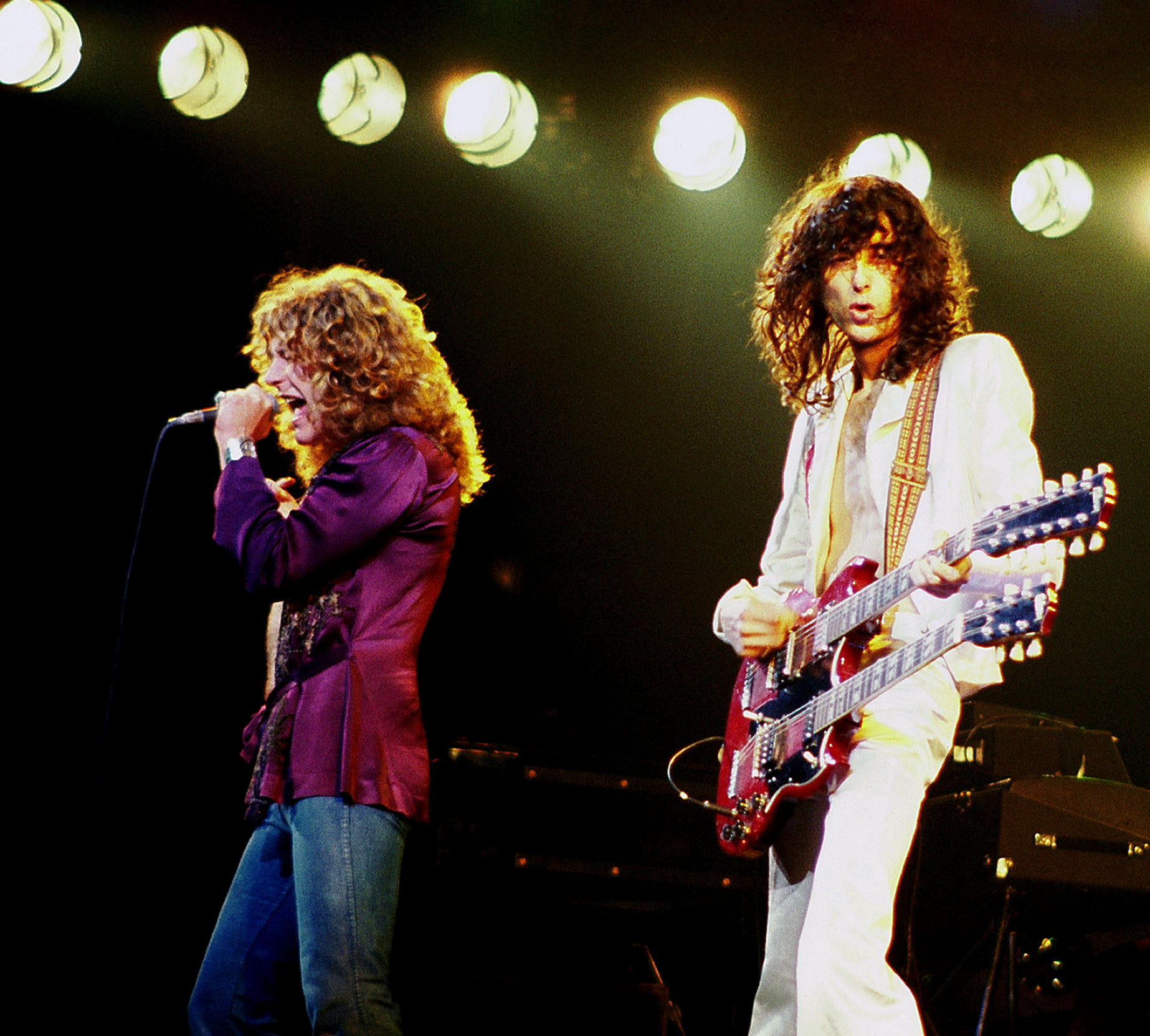 Robert Plant canta al microfono accanto al chitarrista Jimmy Page durante un concerto dei Led Zeppelin nel 1977