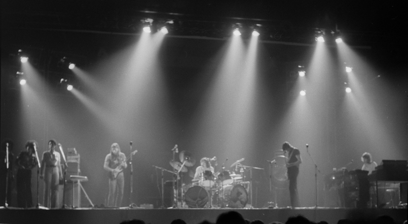 Pink Floyd sul palco dell'Earls Court nel 1973, con musicisti, batteria e coriste sotto fasci di luce