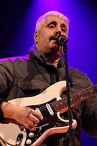 Pino Daniele canta al microfono con una chitarra elettrica bianca nel 2009