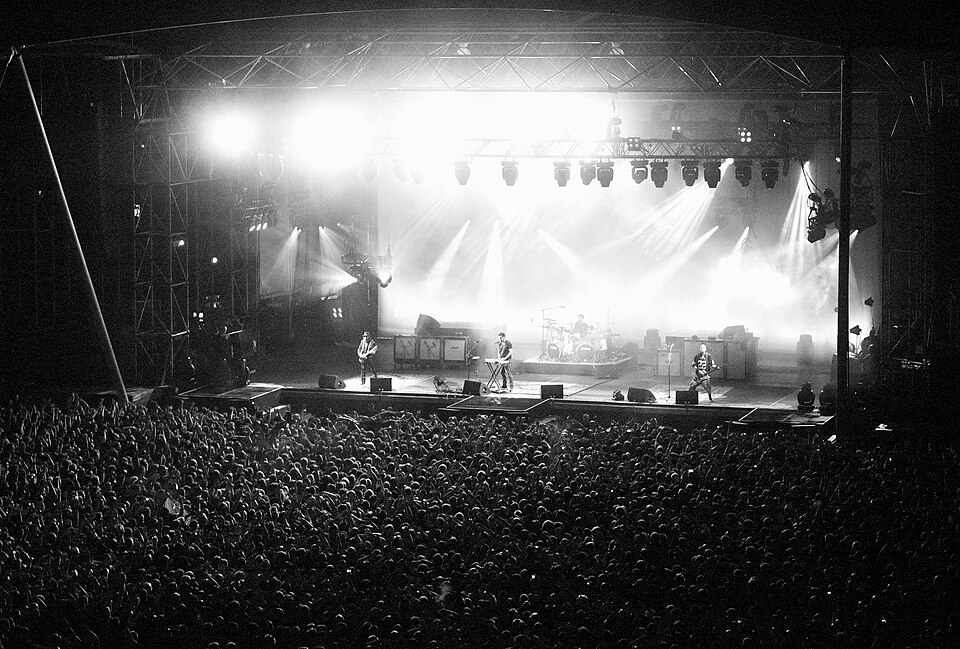 I System of a Down sul palco nel 2013, in una fotografia in bianco e nero con le luci del concerto e il pubblico